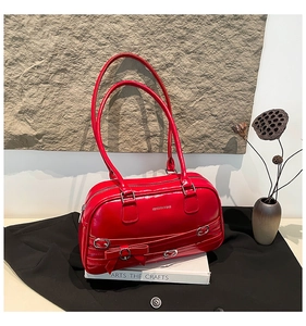 Détail du sac à bandoulière en cuir verni rouge avec nœud et boucles décoratives