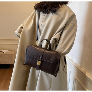 Detail of vintage dark brown leather crossbody bag with retro gold metal clasp on a model