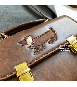 Detailed close-up of textured leather handbag with gold clasp and dog embroidery