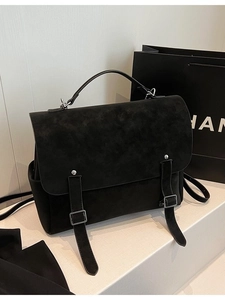 Bolso satchel clásico negro mate con asa superior y hebilla de metal en soporte de exhibición