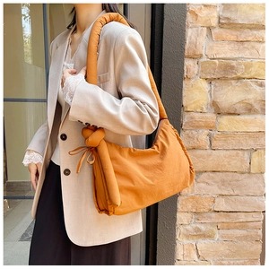 Detail of orange padded nylon tote bag featuring a unique knotted shoulder strap design