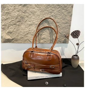 Détail d'un sac bandoulière en cuir marron avec boucle argentée et petit nœud élégant