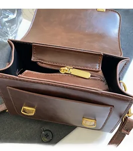 Detailed shot of smooth golden zipper closure and brown leather interior of square bag
