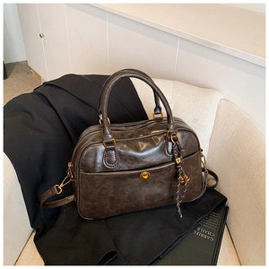 Close-up of vintage brown leather Boston bag with golden hardware and textured finish