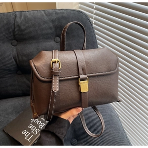 Detail of vintage brown leather bag with contrast stitching and golden clasp buckle