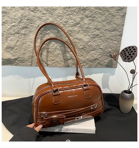 Détail du sac à épaule en cuir verni marron avec nœud décoratif et anneaux métalliques