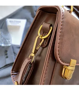 Detail view of vintage brown leather handbag with antique gold hardware and clasp