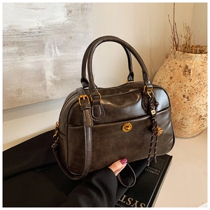Detail of dark brown vintage Boston bag with metal twist lock and decorative M charm