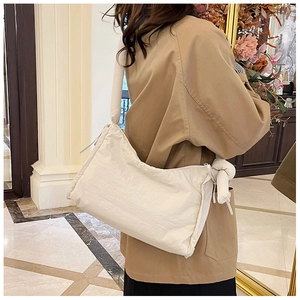 Detail view of large white nylon crossbody bag with stylish knot decorative strap