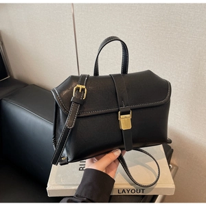 Close-up of black retro handbag with contrast white stitching and gold buckles