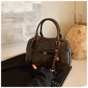 Detail of vintage brown leather boston bag with golden twist lock and woven bell pendant