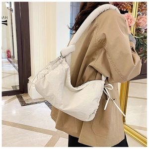 Detail of off-white padded nylon shoulder bag featuring drawstring and knot straps