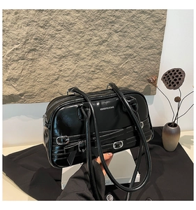 Détail d'un sac à main noir verni avec boucles argentées et nœud décoratif élégant