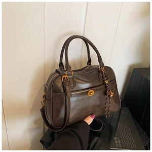 Macro detail of dark brown retro Boston bag with gold hardware and M-pendant