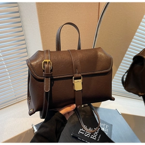 Detail of vintage brown shoulder bag showing white stitching and gold metal buckle hardware