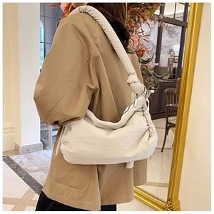 Detail of puffy nylon knot shoulder bag in cream white showing pleated texture and soft strap