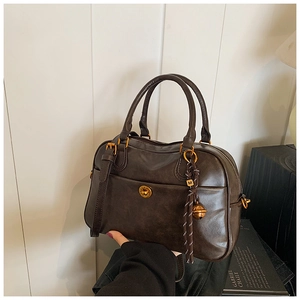 Detail of vintage coffee leather Boston bag with gold hardware and logo pendant