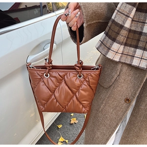 Détail d'un sac seau matelassé marron avec anses nouées et bandoulière réglable