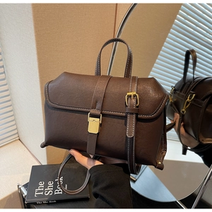 Detail view of vintage dark brown handbag with white stitching and brass hardware