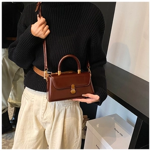 Close-up of vintage dark brown leather crossbody bag with antique bronze clasp buckle