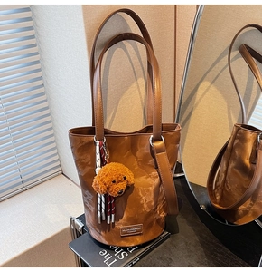 Detail of vintage brown bucket bag with plush dog charm and textured leather straps