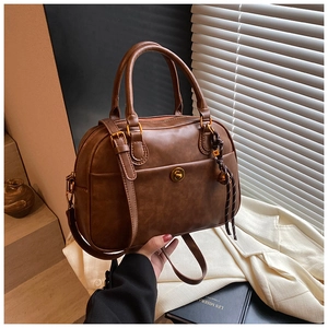 Detail of a retro brown boston bag with a golden turn-lock pocket and woven knot detail