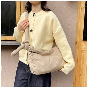 Macro detail of casual beige nylon tote bag with side pleats and knotted strap design