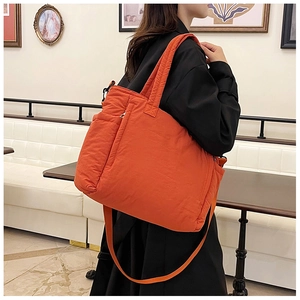Orangefarbene gesteppte Nylon-Tragetasche mit verstellbarem Schultergurt im Café