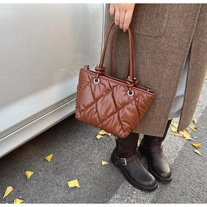 Gros plan du sac cabas matelassé marron avec motif à losanges et détails de nœuds tressés