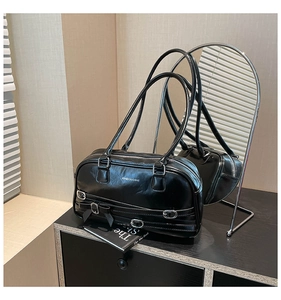 Détail du sac Boston en similicuir noir brillant avec boucle argentée et nœud latéral