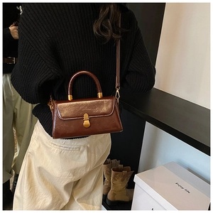 Detail of vintage brown leather handbag with gold metal clasp and adjustable strap