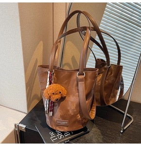 Detail of vintage brown bucket bag with textured faux leather and plush dog charm