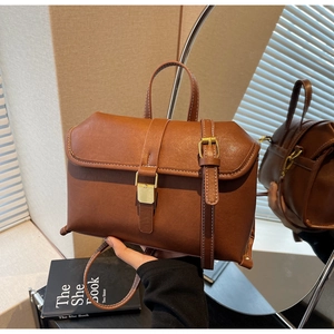 Detailed close-up of brown vintage leather crossbody bag with decorative white stitching