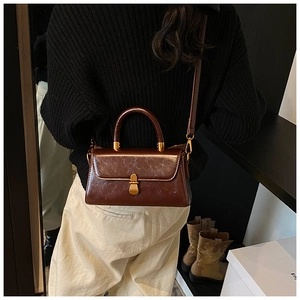 Rear view of a model wearing a vintage dark brown leather crossbody bag with gold buckle