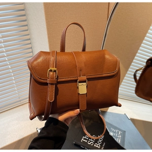 Detail of vintage brown crossbody bag with white stitching and metallic buckle clasp