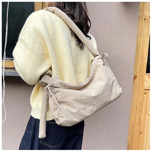 Detail of knot decoration and nylon fabric texture on beige crossbody shoulder bag