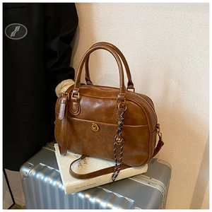 Detailed view of brown retro Boston bag with gold hardware on a vintage suitcase