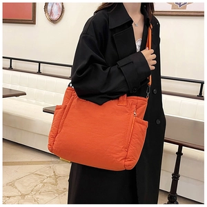 Orangefarbene gesteppte Puffer-Tasche mit verstellbarem Gurt und seitlicher Tasche im Detail