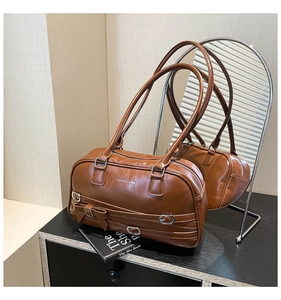 Gros plan du sac Boston marron avec sangles à boucles et texture en similicuir poli