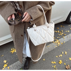 Détail du sac seau matelassé blanc avec poignée nouée et texture en décor d'automne