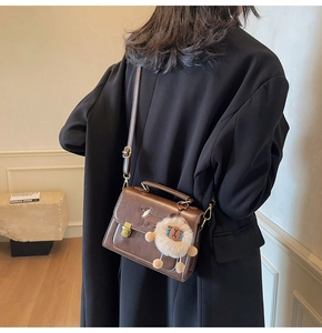 Brown faux leather crossbody bag detail featuring puppy embroidery and plush lamb charm