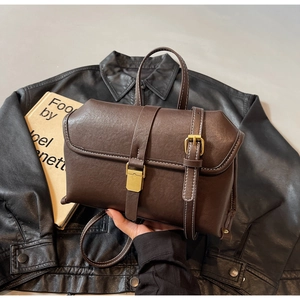 Detail of dark brown vintage handbag with contrast stitching and golden clasp