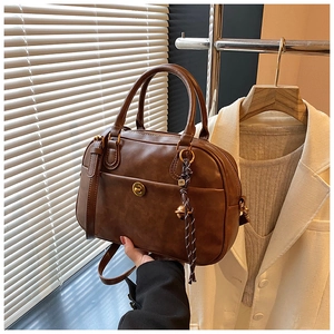 Detail of vintage brown leather pillow bag featuring metal clasp and woven bell ornament