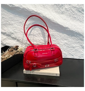 Gros plan détaillé du sac Boston rouge brillant avec nœud sur un fond minimaliste