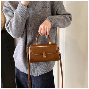 Detailed view of vintage brown leather square bag with golden buckle and round handle