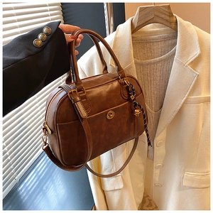 Macro detail of dark brown Boston bag with vintage gold hardware and woven bell charm
