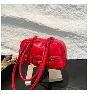 Gros plan d'un sac oreiller en cuir verni rouge vif avec boucles argentées et sangles