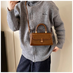Detail of vintage caramel leather handbag with gold clasp and top handle on model