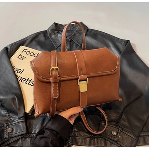 Close-up of brown retro leather handbag with white stitching and gold buckle details