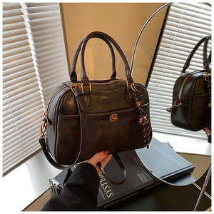 Macro shot of dark brown Boston bag with gold hardware and bell charm detail